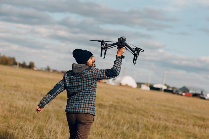 Back view of a man in hoodie holding a drone