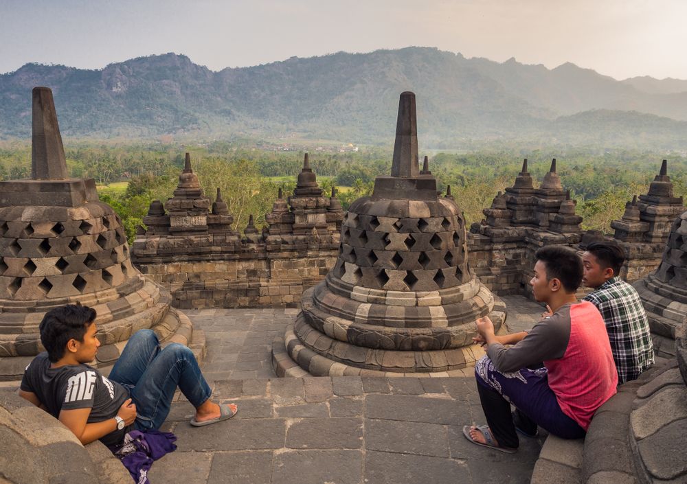Java Island, Indonesia - August, 14 2015: Teenagers in old temple near mountains