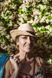Woman standing near a wall with flower shrubs