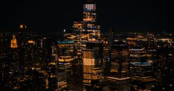 Aerial Helicopter Cinematic Night Scene with a Panoramic View with One World Trade Center Skyscraper and Vibrant Cityscape. Beautiful Office Buildings with Indoors Lights