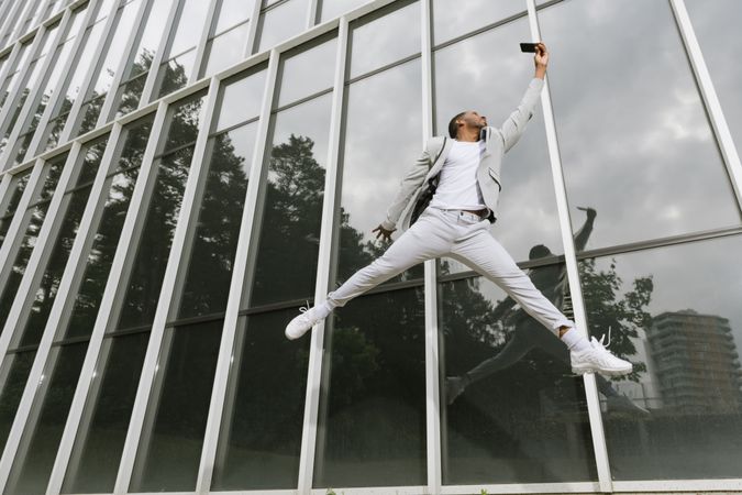 Enthusiastic Black man jumping raising hand like superhero