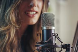 Podcast host recording voice in studio with professional microphone