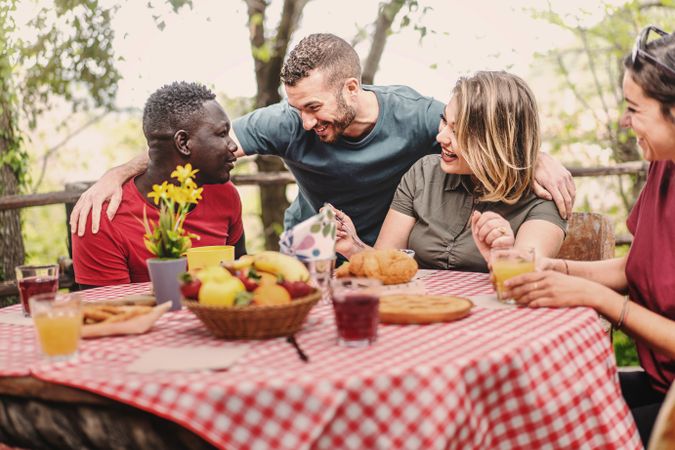 Multi-ethnic group of people gather on farm in the morning for breakfast picnic