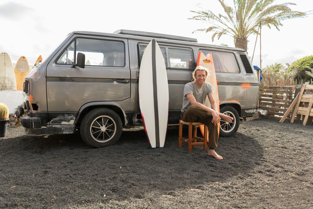 Man standing near surf boards and van