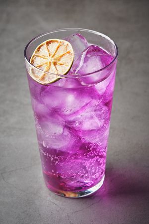 Refreshing drink with purple ice with dehydrated orange slice