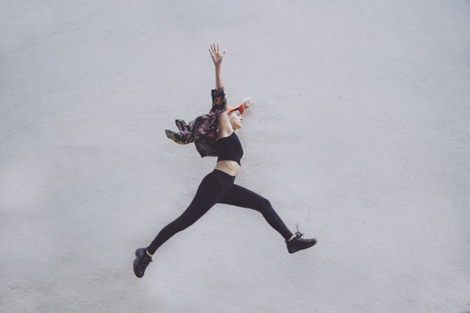 Woman jumping high along wall