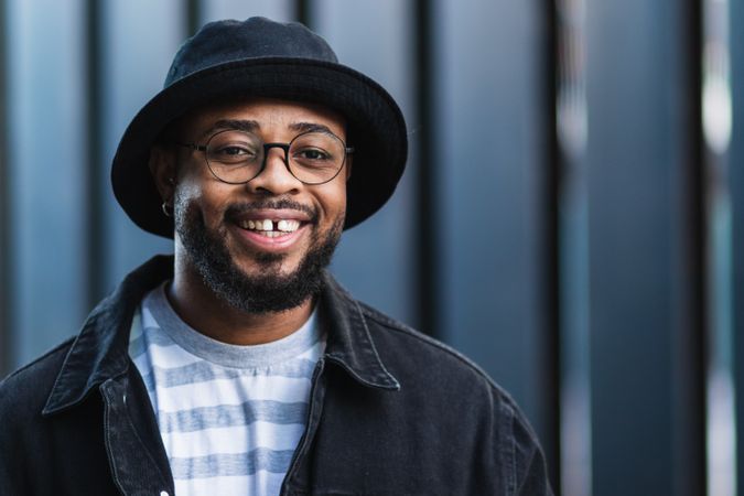 Smiling Black hipster man in hat looking at camera