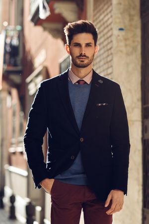 Serious man in the street wearing elegant suit with sun in background
