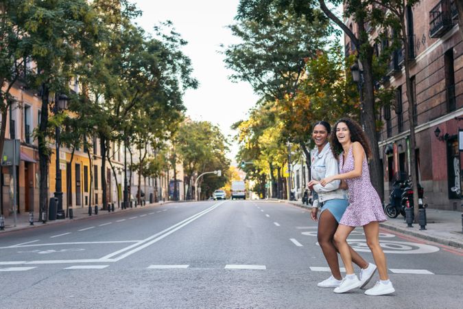 Two women crossing the pedestrian crossing in the city.