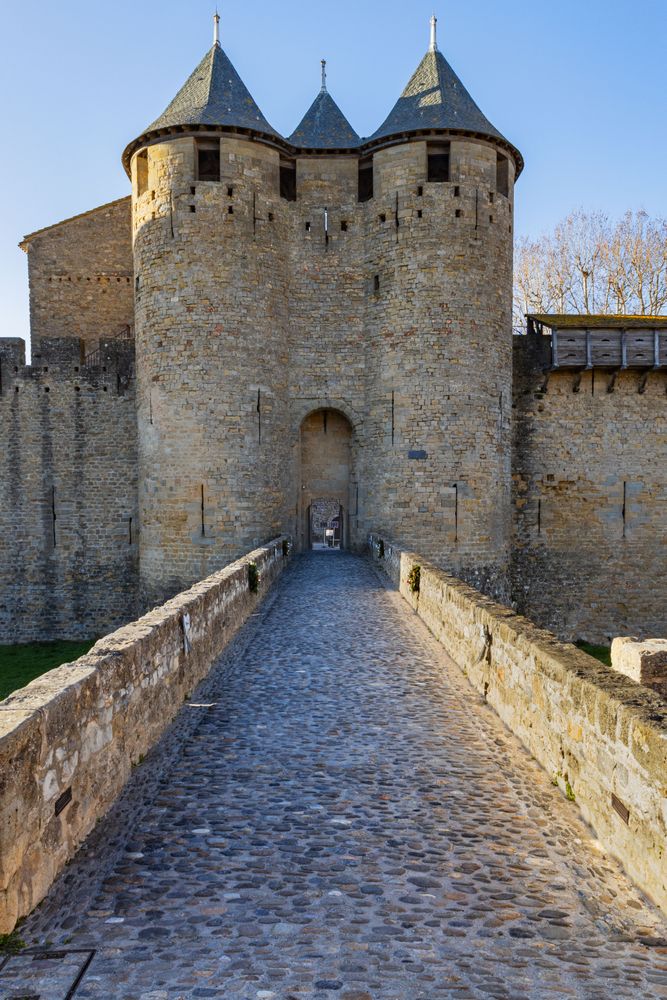 A stone building with a stone bridge leading to it. Access towers to the Castle Comtal in Carcassonne. France