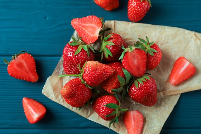 Fresh strawberries and parchment on wooden background, space for text and top view. Summer sweet fruits and berries