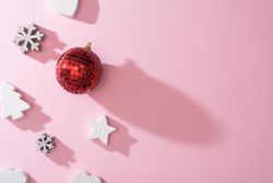 Wooden snowflakes hearts and decorations with red disco ball bauble on pink back with shadows