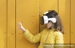 Side view of a girl in yellow jacket wearing VR headset 5zmVN0