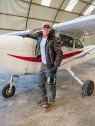 Confident pilot beside retro plane in hangar
