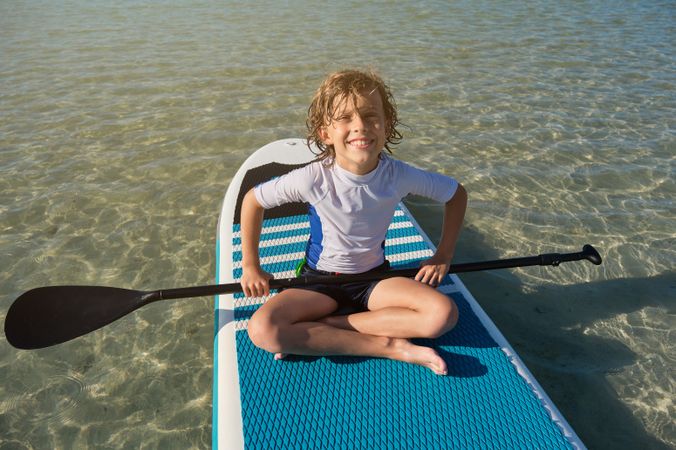 Happy boy relaxing on surfboard in ocean