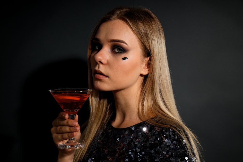 A woman at a party in the style of Halloween with a cocktail in her hands