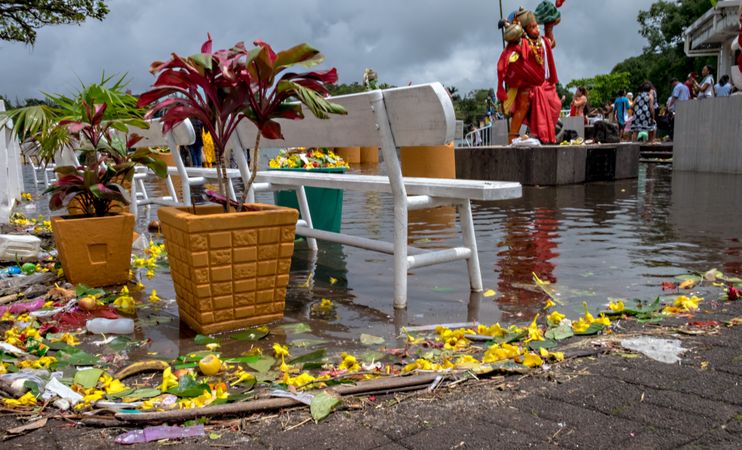 Offerings of fruit and flowers by lake of holy site on cloudy day