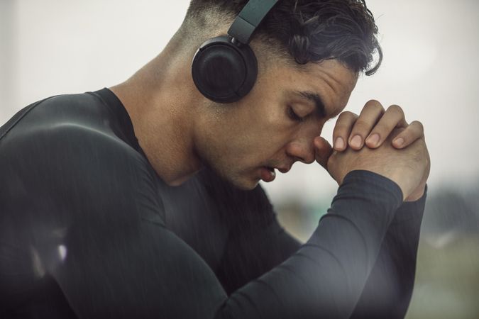 Athletic male sitting with headphones on listening to music before working out