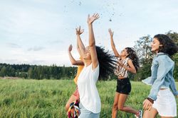 Group of joyful women throwing confetti in a field
