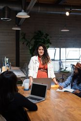 Woman standing at table addressing colleagues in an open work space