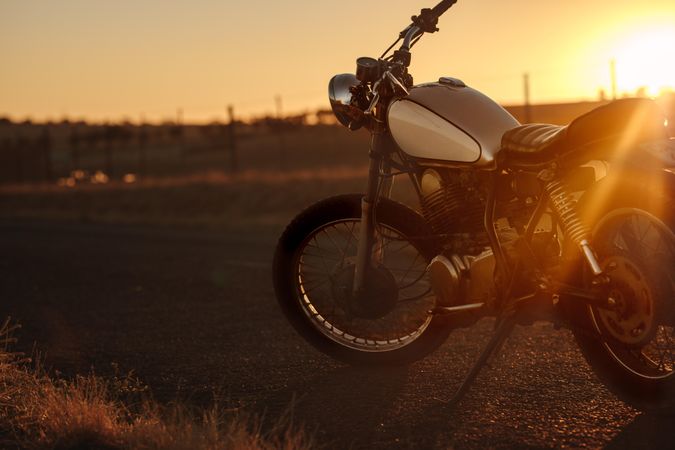 Classic motorbike parked on the road during sunset