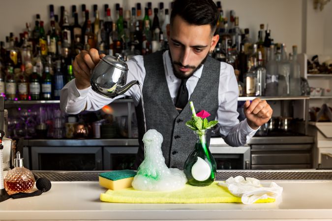 Bartender pouring hot liquid from a pitcher to a special cocktail