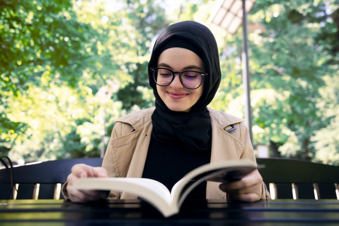 Smiling woman in headscarf with a novel