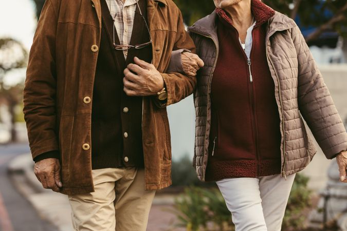 Cropped shot of older couple walking hand in hand outdoors in winter clothing