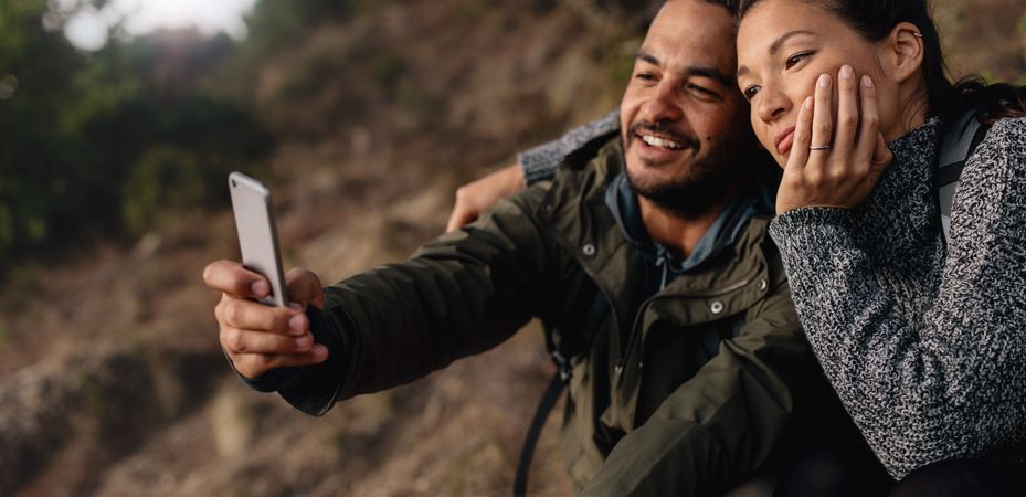 Relaxed hiker couple on holiday taking selfie with cell phone