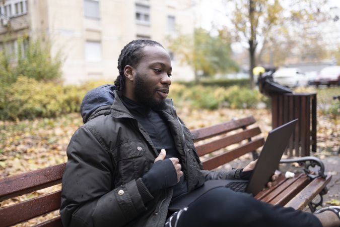 Black Young Man Using Laptop for Online Conversation in Park.
