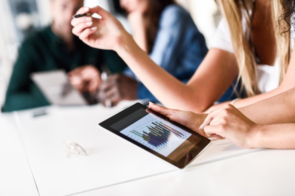 Close up of a group’s hands with group working on tablet