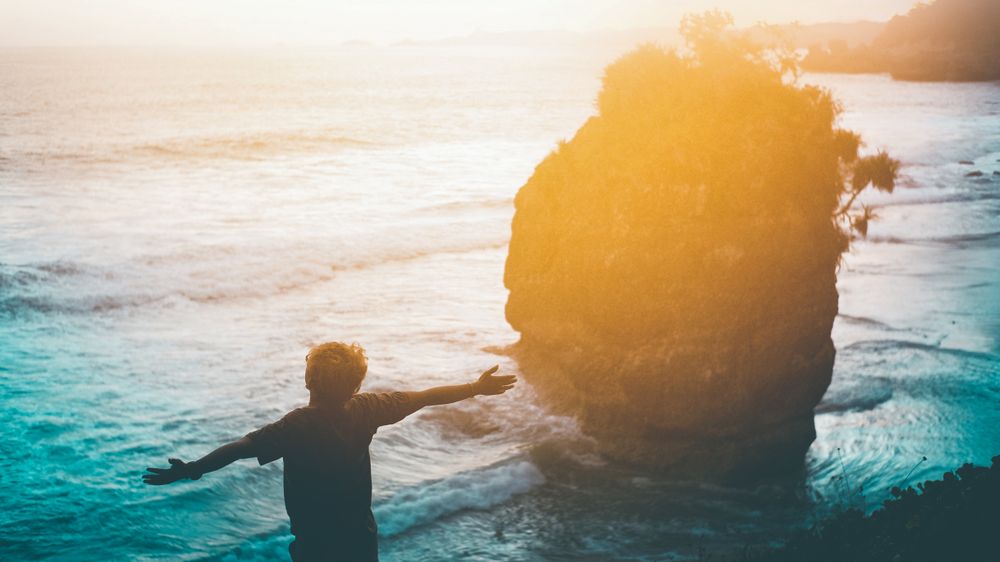 Silhouette of boy standing on the beach during sunset