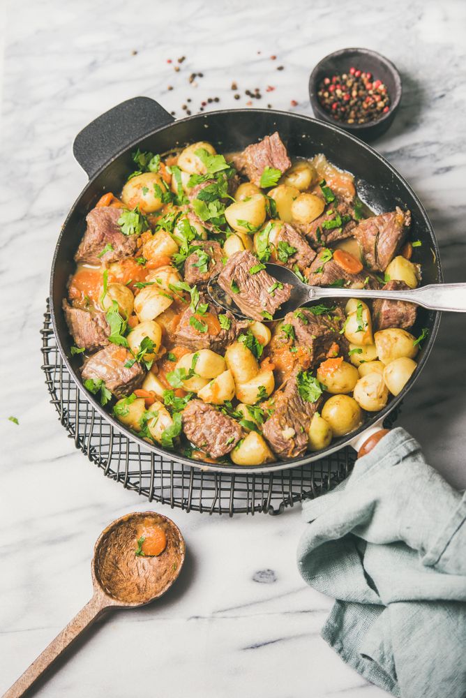 Braised beef stew with potatoes, carrots and parsley, with wooden spoon