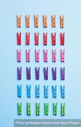 Rainbow colored clothes pins on light blue background 5ayWv5
