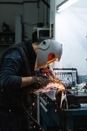Anonymous mechanic welding metal construction in workshop