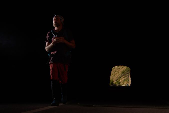 Male traveler walking in dark tunnel and looking forward