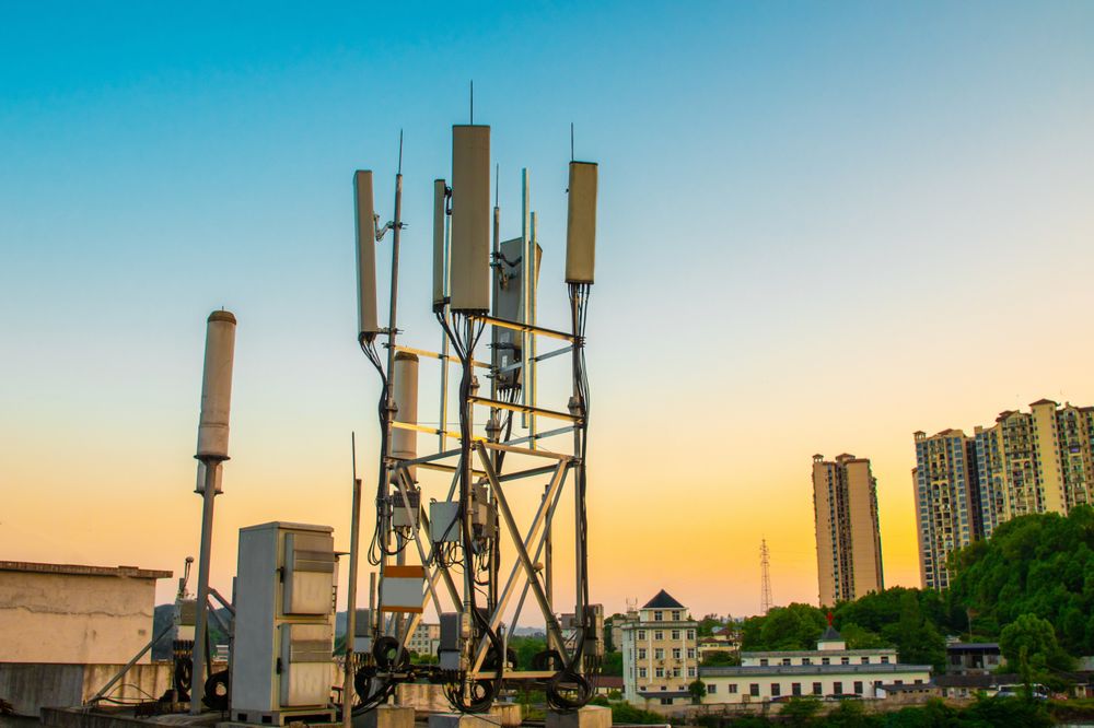 Telecommunication Tower Against a Sunset with Urban and Natural Landscape