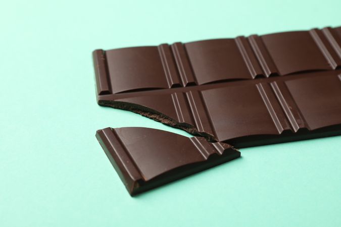 Tasty chocolate bar on mint background. Sweet food