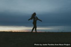 Young woman with long hair spinning in a field at dusk 4AzrNb