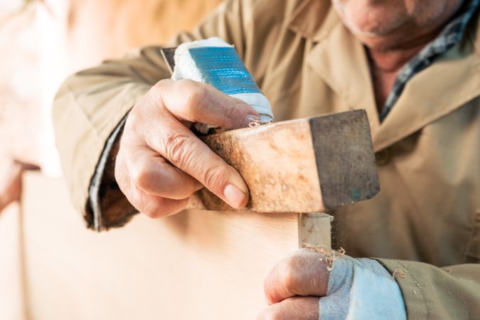 Anonymous man shaping wood with plane tool
