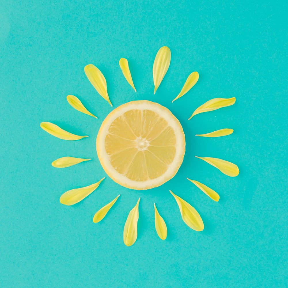 Lemon and yellow flower petals on bright blue background