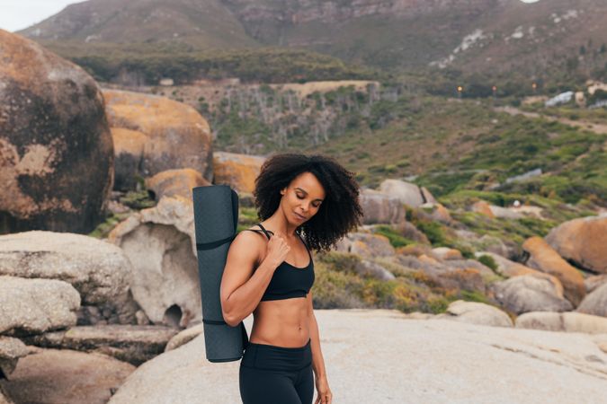 Healthy Black woman with yoga mat in nature