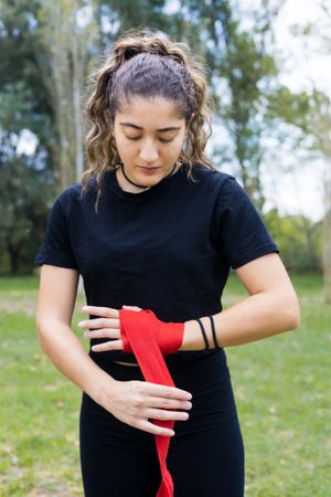 Boxer woman wrapping hands bandage for boxing outdoors