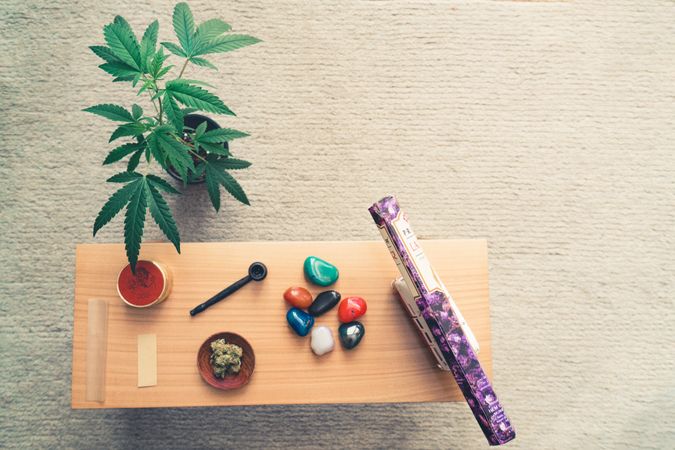 Desk with smoking paraphernalia and crystals next to plant