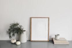 Wooden frame on desk with branches, books and decorative squashes