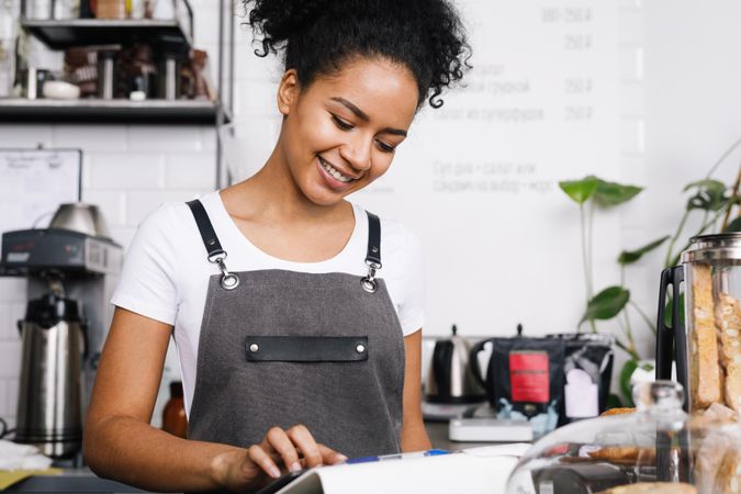 Happy barista using tablet in her shop
