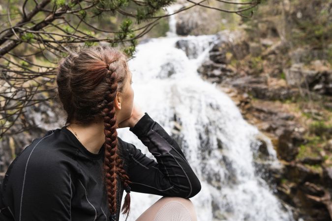 Pensive traveling woman looking away against waterfall
