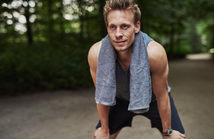 Sporty man leaning down with towel around neck