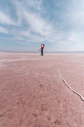 Happy relaxed travelers enjoying unusual scenery of pink salt lake in sunny day