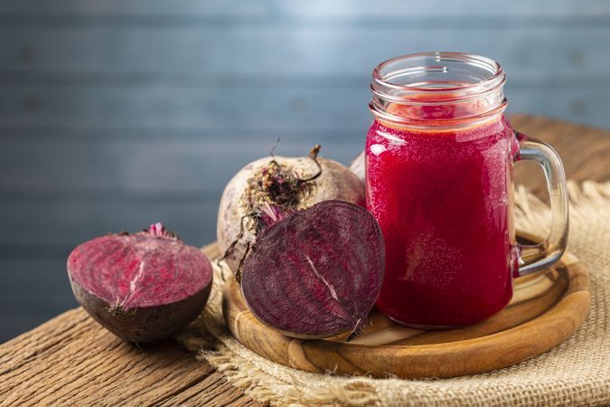 Red beet juice in a glass cup on the wooden table.